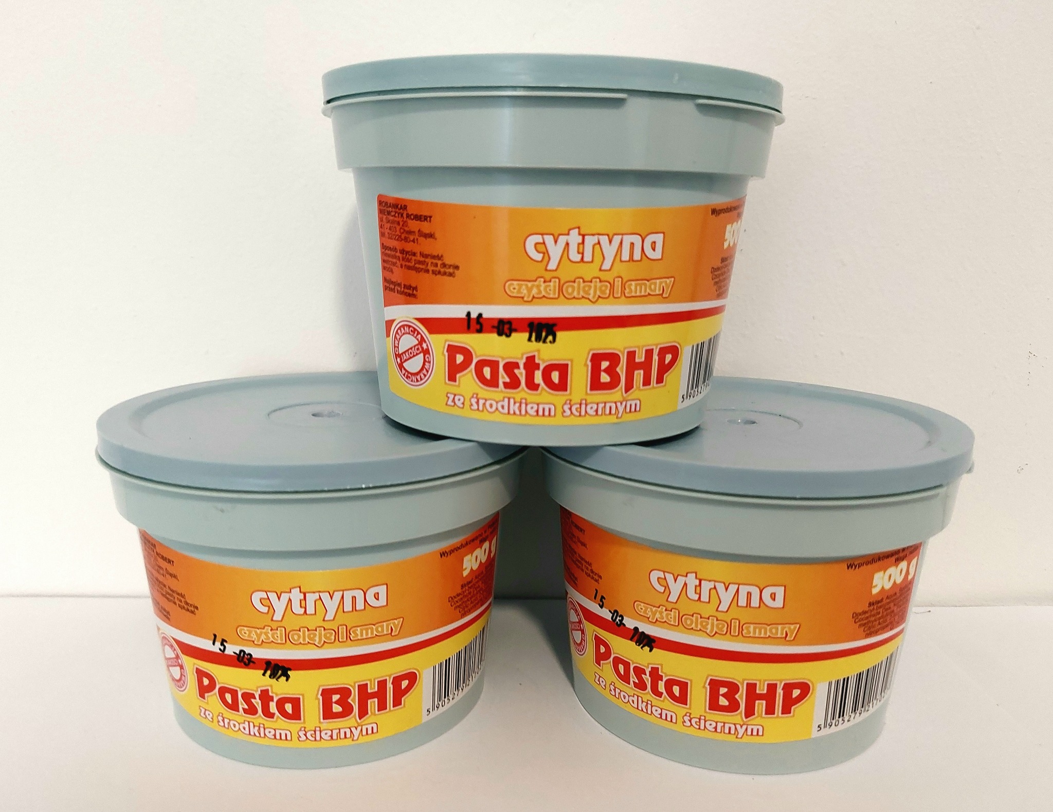 Trzy plastikowe pojemniki z pastą BHP o zapachu cytrynowym, przeznaczoną do czyszczenia olejów i smarów, ustawione jeden na drugim na białym tle.