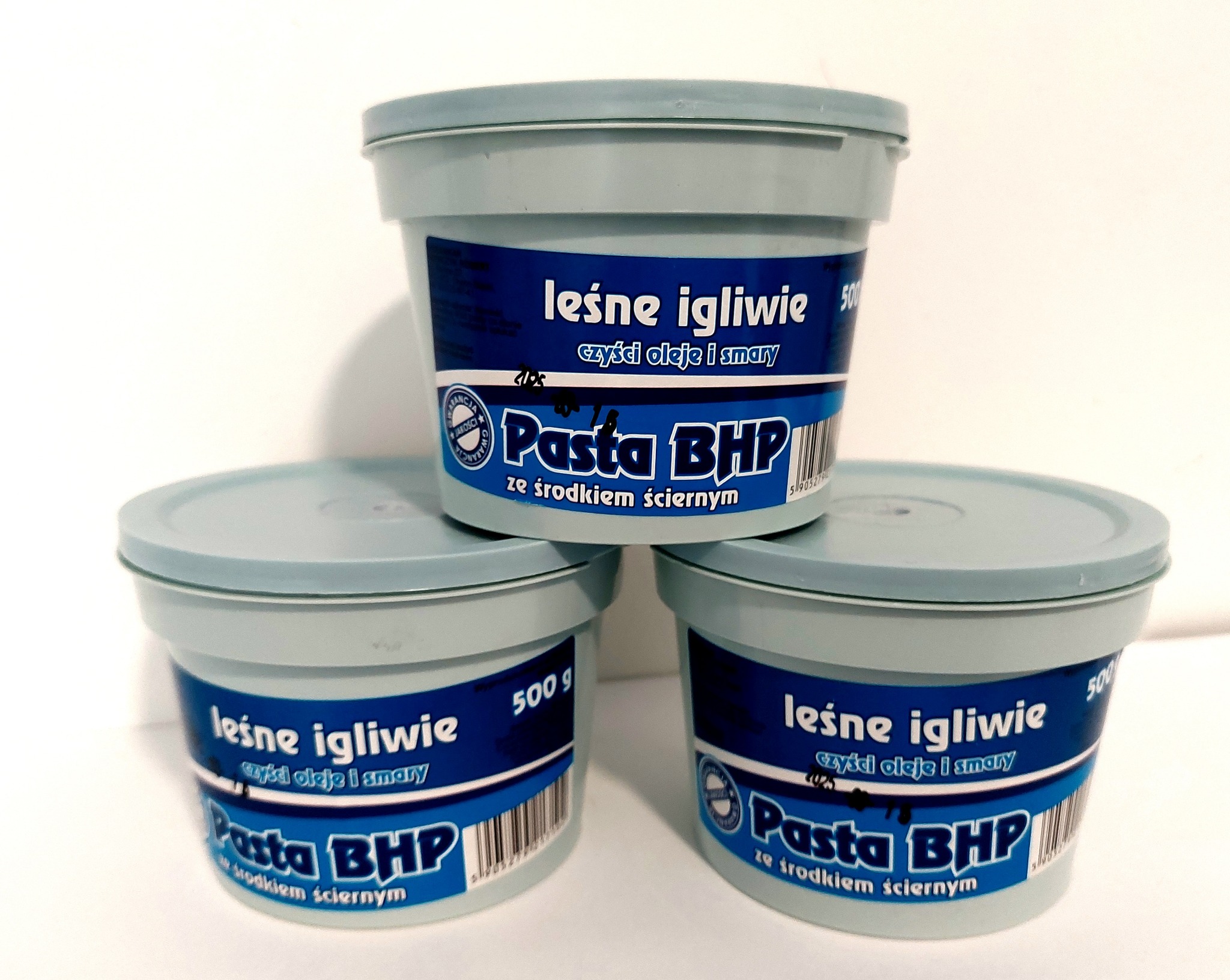 Trzy pojemniki z pastą BHP 'Leśne Igliwie' do czyszczenia olejów i smarów, ustawione jeden na drugim na białym tle.