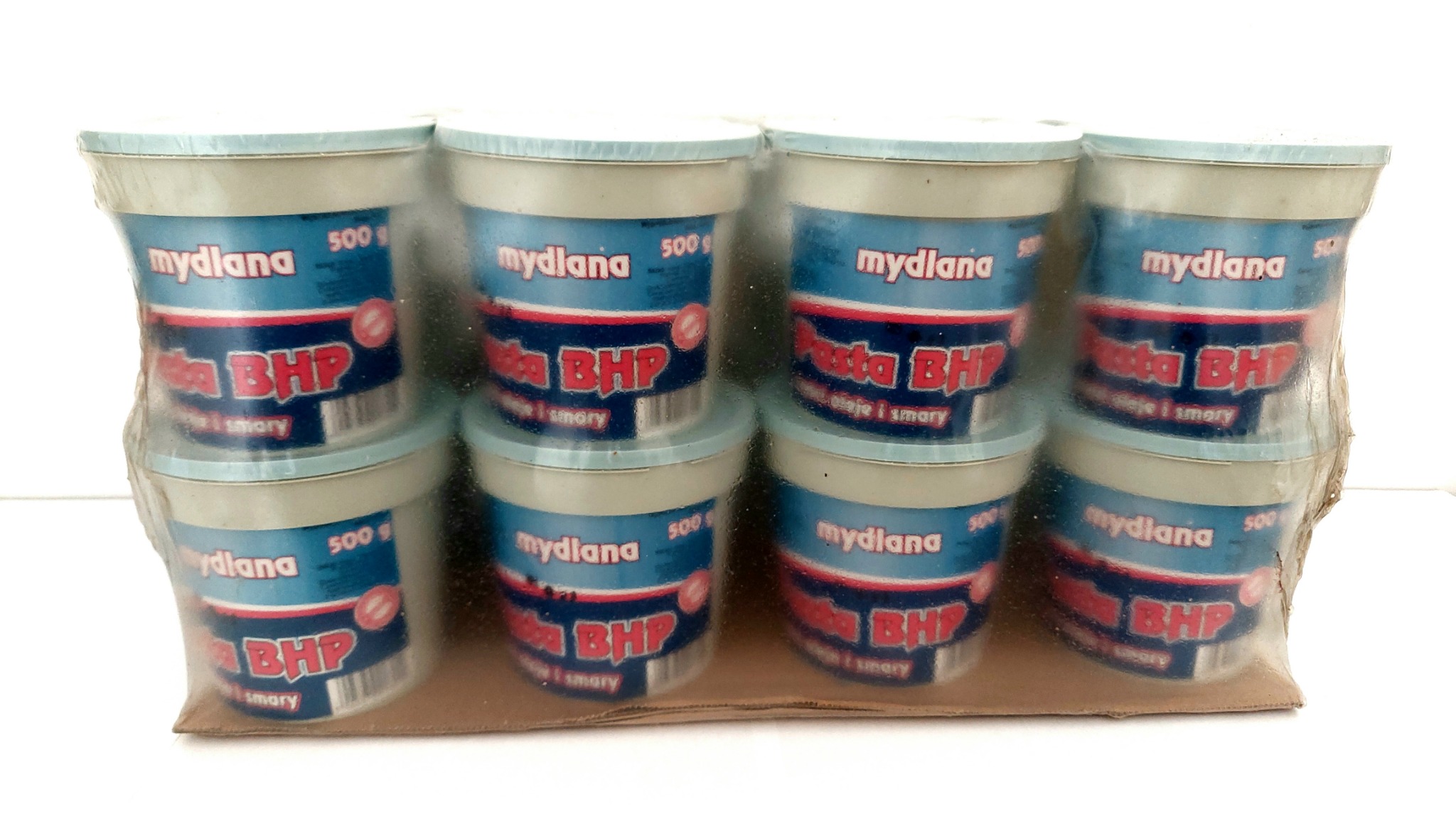 Opakowanie ośmiu pojemników pasty BHP 'mydlana' 500g, zapakowanych w folię, na tekturowej podstawie, widoczne etykiety w kolorze niebieskim i czerwonym.