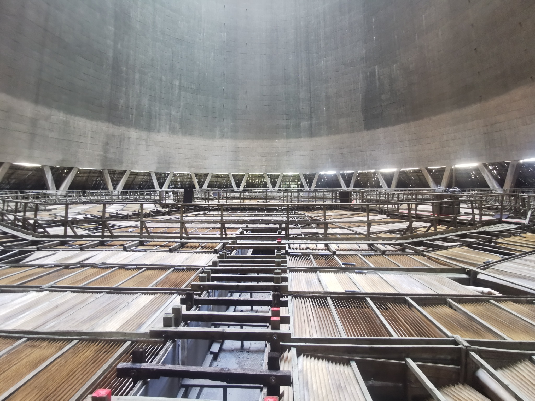 Wnętrze chłodni kominowej w trakcie budowy lub remontu, widoczne drewniane rusztowania i betonowa konstrukcja kopuły.