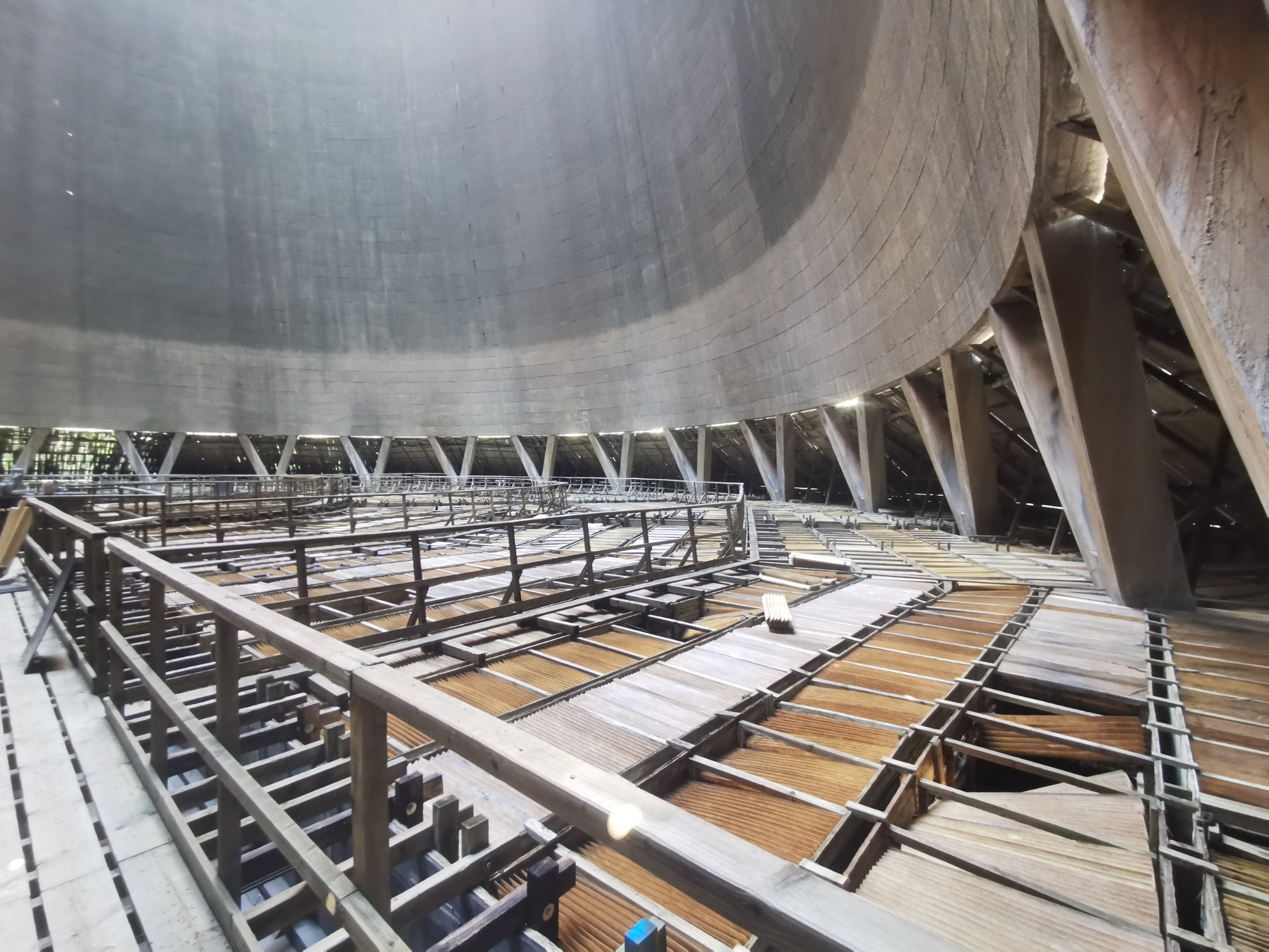 Wnętrze chłodni kominowej w trakcie budowy lub remontu, widoczne drewniane rusztowania i elementy konstrukcyjne pod kopułą.