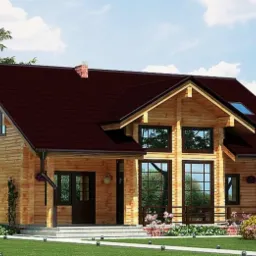 Gotowy, dwukondygnacyjny dom z bali drewnianych z ciemnoczerwonym dachem, otoczony zielonym trawnikiem i kwitnącymi krzewami, widoczny z perspektywy ogrodu.