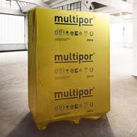 Żółta paleta z zapakowanymi płytami Multipor w magazynie, widoczne logo i oznaczenia produktu, oświetlenie górne, betonowa posadzka.