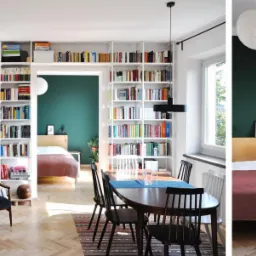 Salon z otwartą przestrzenią do sypialni, białe regały na książki, parkiet w jodełkę, ciemnozielona ściana w sypialni, stół jadalny z krzesłami.