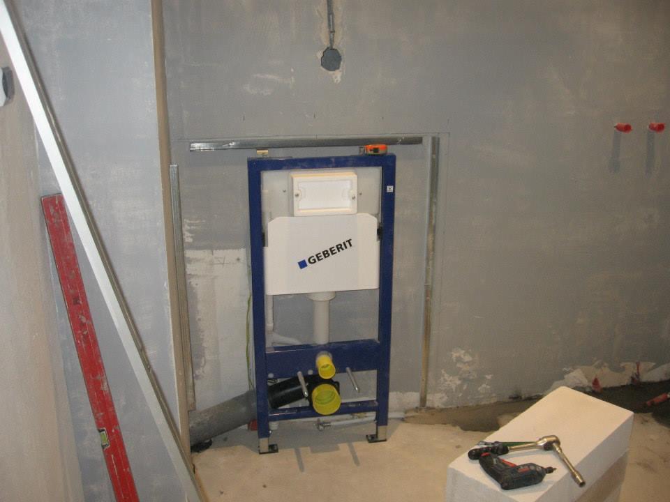 Stelaż podtynkowy Geberit zamontowany w surowej łazience, widoczne narzędzia i poziomica, ściany przygotowane pod wykończenie.