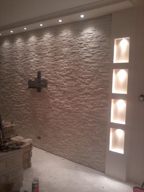 Ściana z dekoracyjnej cegły z podświetlanymi niszami. Wykończenie wnętrza z elementami dekoracyjnymi i oświetleniem punktowym.