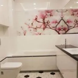 Nowoczesna łazienka z białą armaturą, heksagonalną podłogą w czarno-białe wzory i szklanym panelem ściennym z motywem kwitnącej magnolii nad wanną.