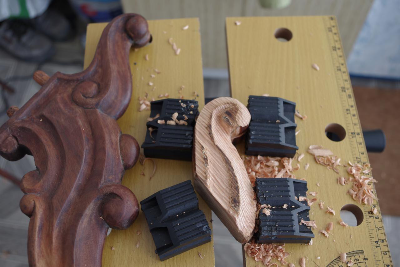 Elementy dekoracyjne z drewna w trakcie renowacji, widoczne ślady obróbki. Fragmenty złączone z użyciem czarnych zacisków stolarskich.
