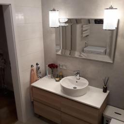 USŁUGI BUDOWLANO-REMONTOWE,LASKOWSKI PIOTR - Nowoczesna łazienka z umywalką nablatową, podświetlanym lustrem i drewnianą szafką z szufladami, uzupełniona o dekoracyjne dodatki jak wazon z czerwonymi różami i zapachowe patyczki.