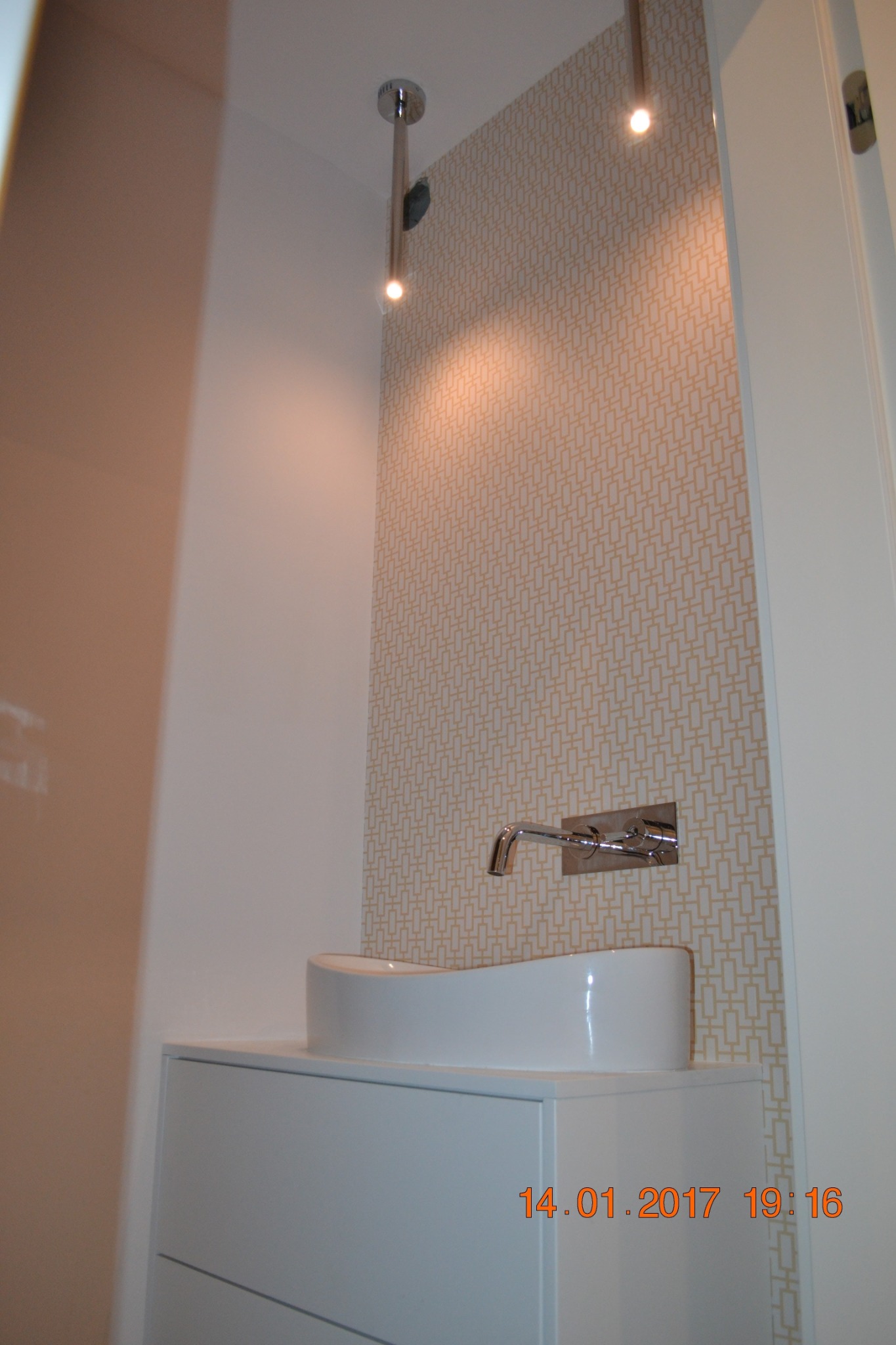 Nowoczesna umywalka nablatowa z chromowaną armaturą na tle wzorzystej tapety i oświetlenia punktowego w Pawłowie. Minimalistyczny design i czyste linie.