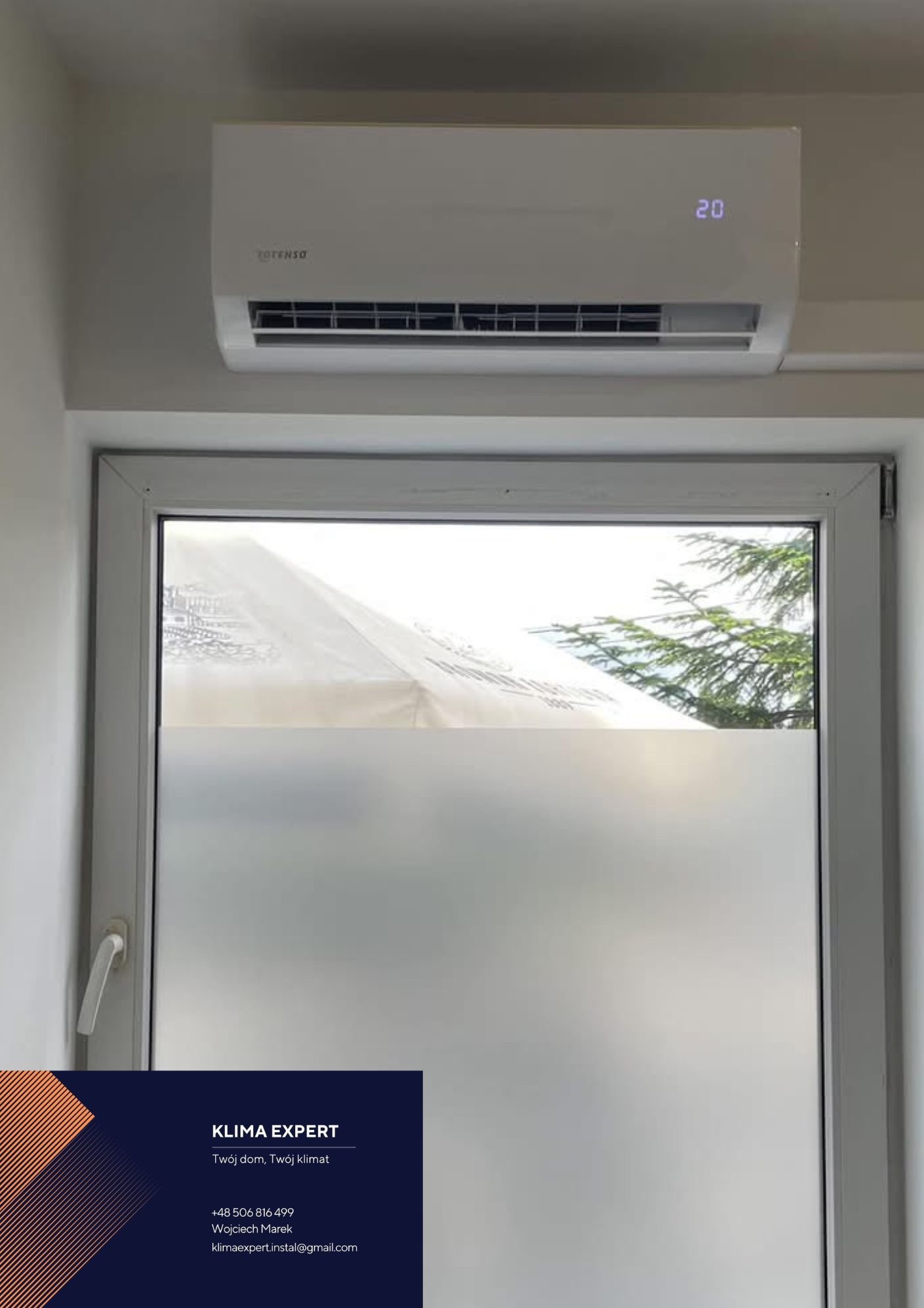 Biały klimatyzator marki Totenso zamontowany nad oknem z naklejoną folią matującą, wyświetlający temperaturę 20 stopni Celsjusza; w rogu wizytówka firmy Klima Expert.