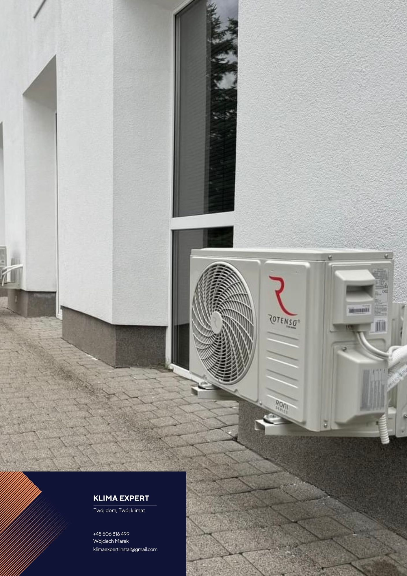 Zamontowany klimatyzator Rotenso na elewacji budynku w Szczyrku, widoczny z boku na tle okna i fragmentu chodnika z kostki brukowej.