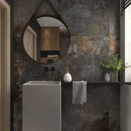 Wizualizacja łazienki z umywalką w kształcie prostopadłościanu, okrągłym lustrem na pasku, płytkami imitującymi rdzę i roślinami w szklanym wazonie.