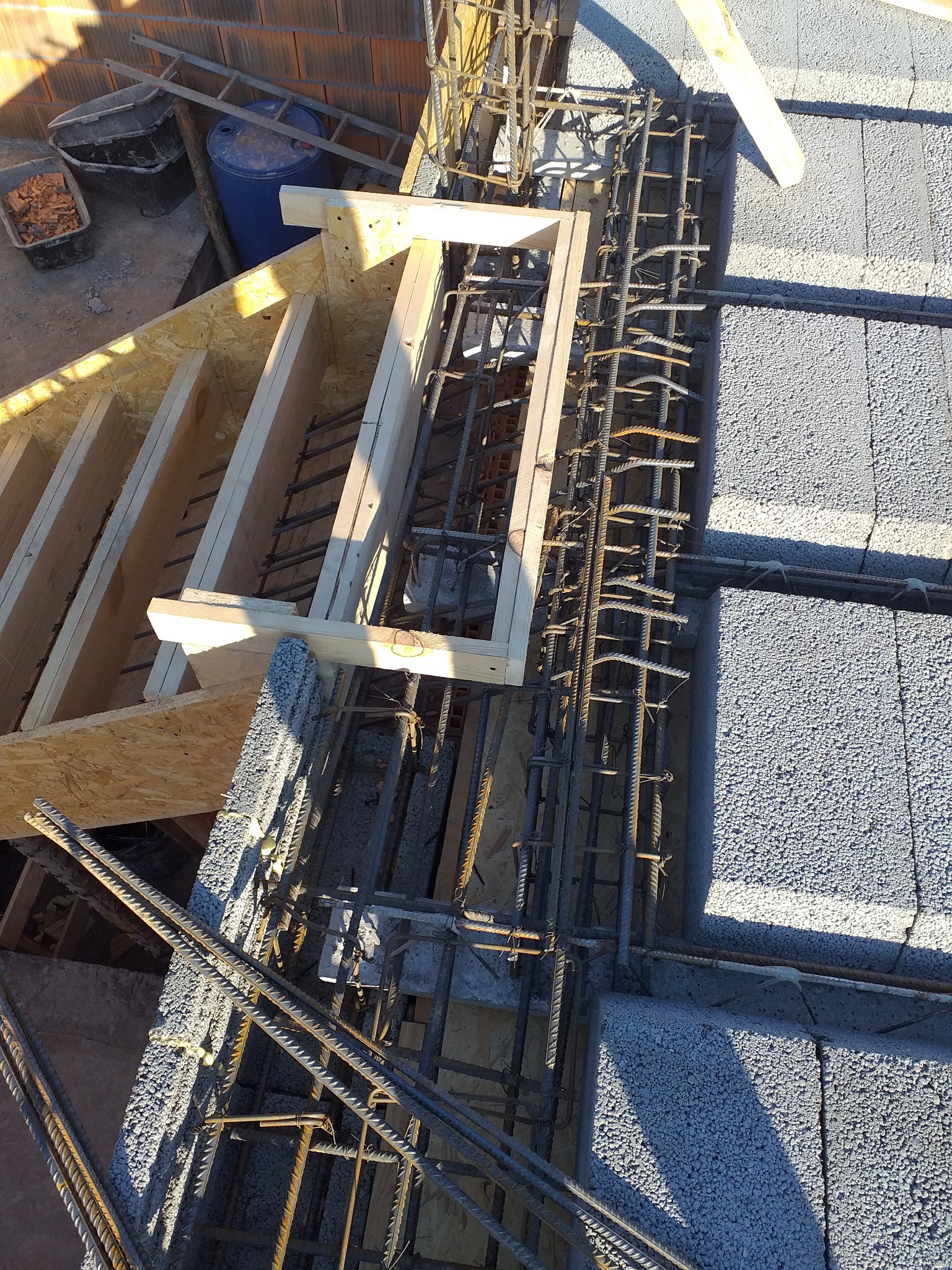 Zbrojenie wieńca na bloczkach betonowych, widoczne szalunki drewniane i pręty stalowe, ujęcie z góry.