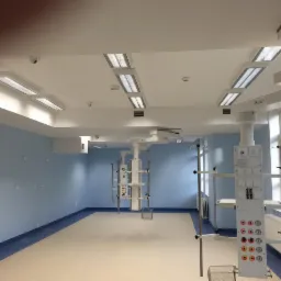 Jasne wnętrze nowej sali operacyjnej z niebieskimi ścianami i nowoczesnym oświetleniem sufitowym oraz sprzętem medycznym.