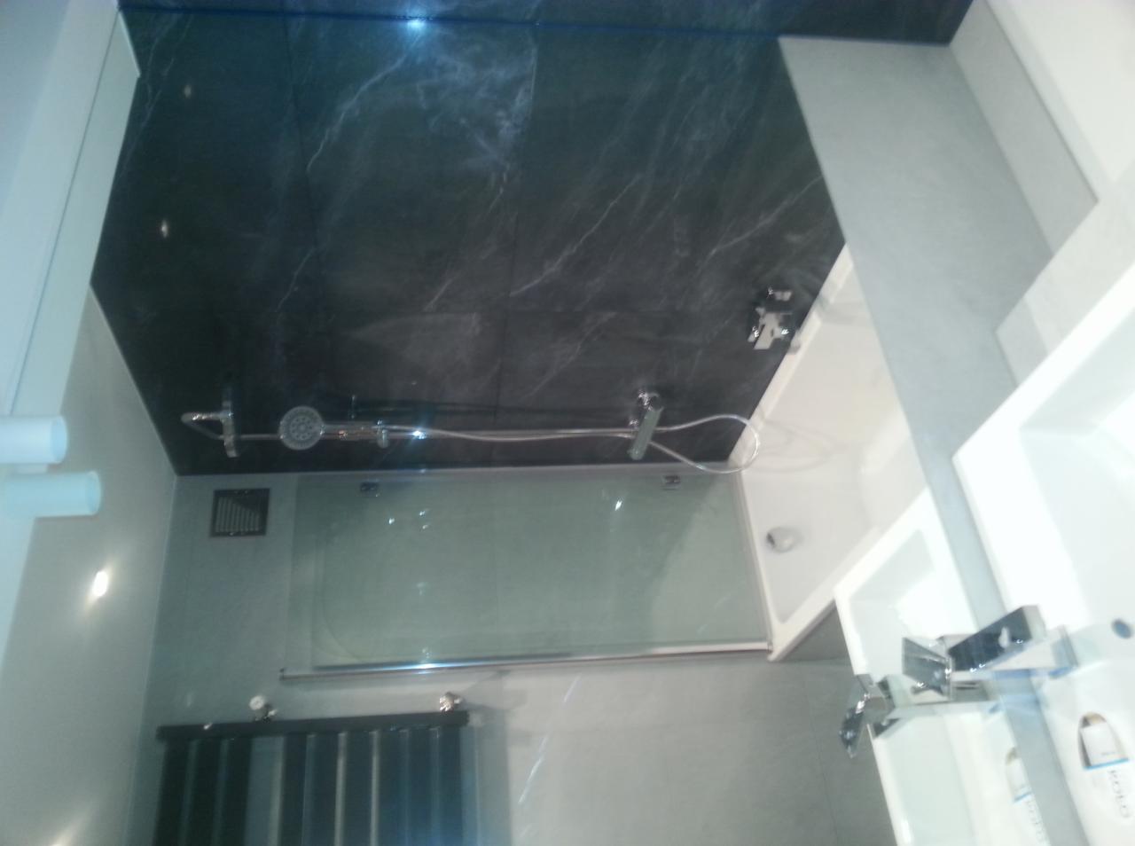 Nowoczesna łazienka z kabiną prysznicową, umywalką i czarnym sufitem z marmurkowym wzorem. Widoczne detale armatury i oświetlenia.