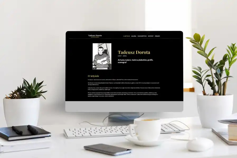 Monitor wyświetlający stronę internetową artysty Tadeusza Doroty na białym biurku, z roślinami i filiżanką kawy w tle. Minimalistyczny design, czarne tło strony.
