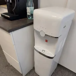 Ekspres do kawy i dystrybutor wody stoją obok siebie w Siemiatyczach, na blacie stoi butelka wody.