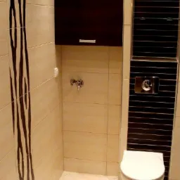 Nowoczesna łazienka z beżowymi płytkami, czarnym akcentem i wiszącą szafką. Uwagę zwraca wz&oacute;r zebry na ścianie i minimalistyczny design armatury.