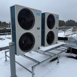 SM SYSTEM - Dwie jednostki zewnętrzne klimatyzacji Midea Multi MAX na dachu pokrytym śniegiem, zamontowane na metalowej konstrukcji wsporczej. Widoczne drzewa w tle.