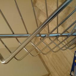 Kamil Rybiński- Usługi GREENI - Mop parowy z niebieską nakładką z mikrofibry, oparty o marmurowe schody, widziany z góry spod chromowanej barierki schodowej, podczas sprzątania wnętrza.