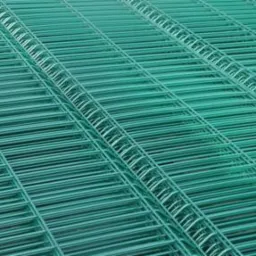 Zielone panele ogrodzeniowe z drutu, ułożone ukośnie, tworzące regularny wzór. Widoczna faktura i detale spawów. Delikatne cienie podkreślają strukturę.