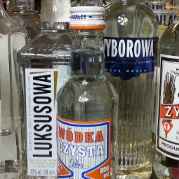 Różne butelki wódki polskich marek, m.in. Baczewski, Luksusowa, Wyborowa i Żytnia, ustawione obok siebie. Widoczne etykiety i kształty butelek.