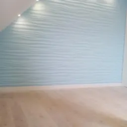 Błękitna ściana z falistym wzorem 3D, oświetlona punktowymi lampami sufitowymi, z jasną drewnianą podłogą.