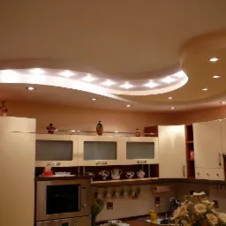 Jasna kuchnia z beżowymi szafkami i podwieszanym sufitem z oświetleniem punktowym. Dekoracje na szafkach dodają wnętrzu przytulności.