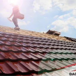 Praca na dachu: dekarz układa brązowe, błyszczące elementy pokrycia na drewnianej konstrukcji, w tle błękitne niebo z chmurami i jasne słońce, w prawym dolnym rogu logo firmy.