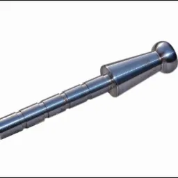 Metalowy element obrobiony na tokarce z widocznymi śladami obr&oacute;bki, stożkowym kształtem i zaokrąglonym zakończeniem. Widoczne schodkowe przejścia średnic.