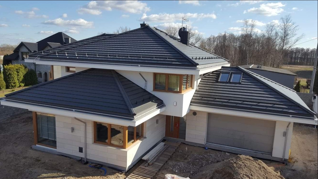 Nowoczesny dom jednorodzinny z ciemnoszarą dachówką w Mińsku Mazowieckim, widok z góry na ukończony dach z oknami dachowymi i obróbkami blacharskimi.