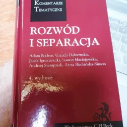 Czerwona książka 'Sądowe Komentarze Tematyczne: Rozw&oacute;d i Separacja', czwarte wydanie, leżąca na biurku obok laptopa.