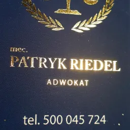 Wizytówka adwokata Patryka Riedla z złotym symbolem wagi i numerem telefonu na ciemnoniebieskim tle.