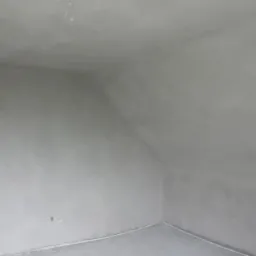 Wnętrze pomieszczenia po nałożeniu gładzi gipsowej, widoczny sufit skośny, ściany i podłoga w odcieniach szarości, świeżo wykończone, gotowe do malowania.