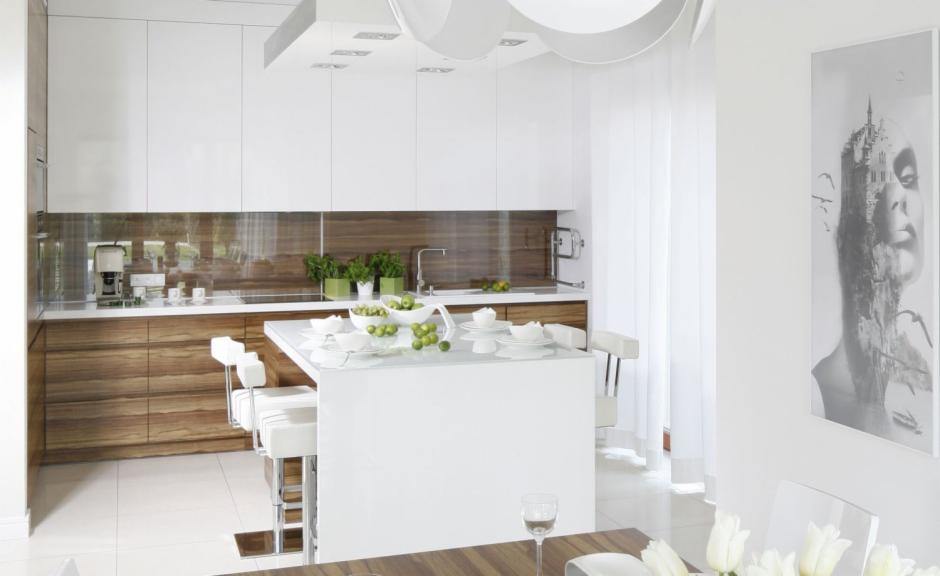 Nowoczesna kuchnia z wyspą, białe szafki górne i drewniane dolne, minimalistyczny design, oświetlenie sufitowe, obraz na ścianie.