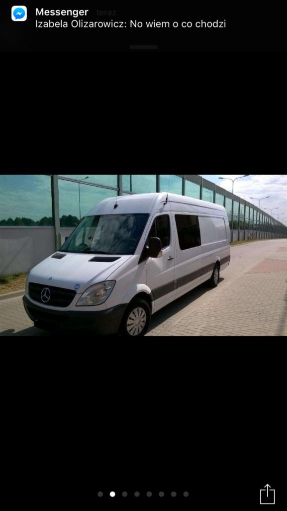 Biały bus marki Mercedes-Benz Sprinter, widok z boku na tle drogi z barierkami dźwiękochłonnymi. Charakterystyczne logo Mercedesa na masce.