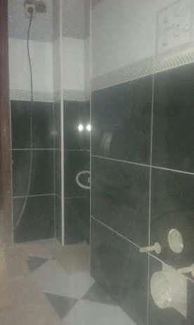 Wykończona łazienka z czarnymi płytkami, kabiną prysznicową i wzorzystą podłogą. Widoczne detale wykończeniowe i armatura.