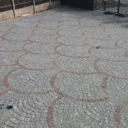 Ułożona kostka granitowa w oryginalny wzór wachlarzy z czerwonymi akcentami, tworząca podjazd do posesji z metalową bramą i betonowym ogrodzeniem.