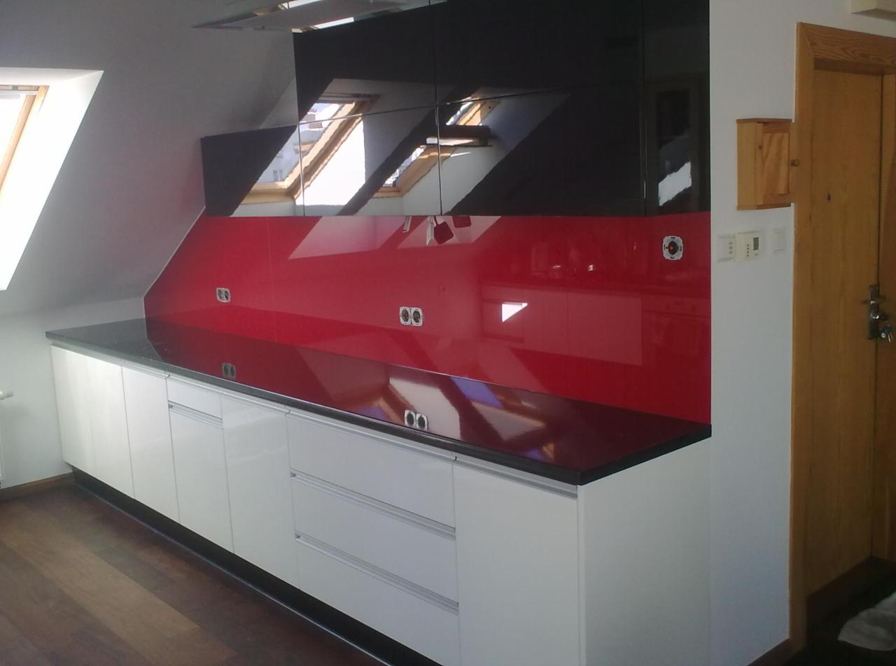 Nowoczesna kuchnia z białymi szafkami i czerwono-czarnym panelem szklanym na ścianie, odbijającym okna dachowe. Minimalistyczny design.