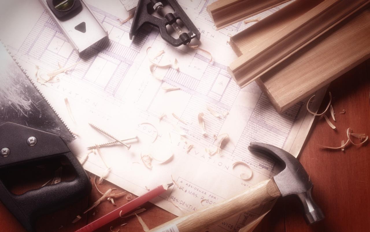 Plan architektoniczny z narzędziami: piła, młotek, poziomica, śruby, ołówek, drewniane listwy i wióry. Przybory rozłożone na stole.