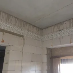 Surowy stan wnętrza w trakcie instalacji przewodów wentylacyjnych pod sufitem, widoczne ślady po wierceniu i mocowaniu na ścianach z betonu komórkowego.