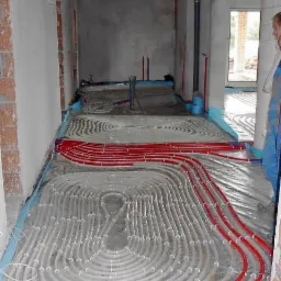 Instalacja ogrzewania podłogowego, rury grzewcze ułożone na izolacji w Grudziądzu. Widok na surowy stan budynku w trakcie prac instalacyjnych.