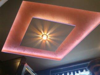 Oświetlenie sufitowe z kwadratowym panelem centralnym i dekoracyjnym, różowym podświetleniem LED na krawędziach, tworzące efektowny wzór świetlny.