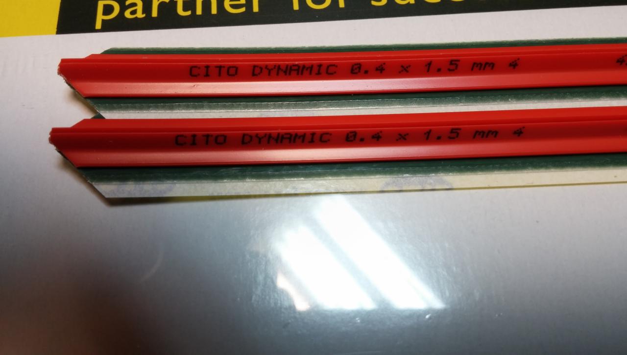 Dwa paski czerwonej listwy CITO DYNAMIC 0.4 x 1.5 mm 4, widoczne napisy na listwach, zielony pasek pod listwą, ułożone równolegle na jasnej powierzchni.