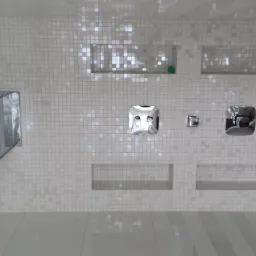 Nowoczesna kabina prysznicowa z armaturą w kształcie kwadratu i mozaiką w odcieniach bieli. Widoczne wnęki w ścianie i deszczownica.