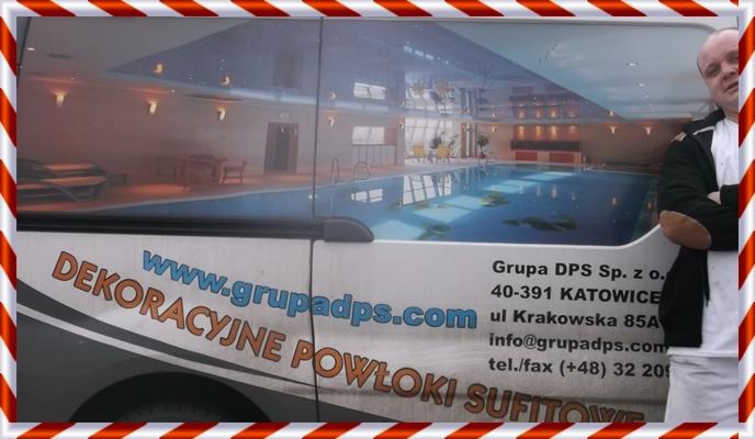 Reklama na samochodzie w Łodzi prezentuje dekoracyjne powłoki sufitowe Grupy DPS z widokiem na basen z oświetleniem. Osoba stoi obok.