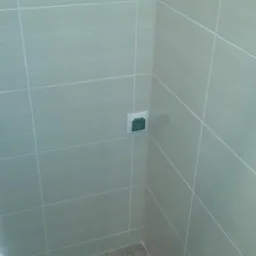 Wykończona łazienka w Zgierzu: beżowe płytki na ścianach i podłodze, widoczne gniazdko elektryczne. Minimalistyczny design, schludne fugi.