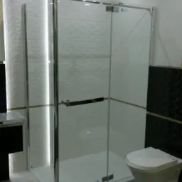 Nowoczesna kabina prysznicowa z chromowanymi profilami i szklanymi drzwiami, białe płytki 3D na ścianach, szara podłoga, minimalistyczny design.