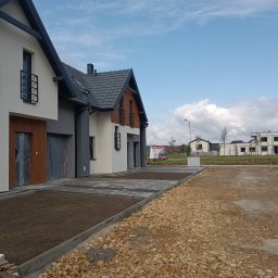 KBKG Budownictwo Grzegorz Luranc - Nowoczesne domy w zabudowie szeregowej w Brzeszczach, z wykończonymi podjazdami i częściowo zagospodarowanym terenem, widok w słoneczny dzień.